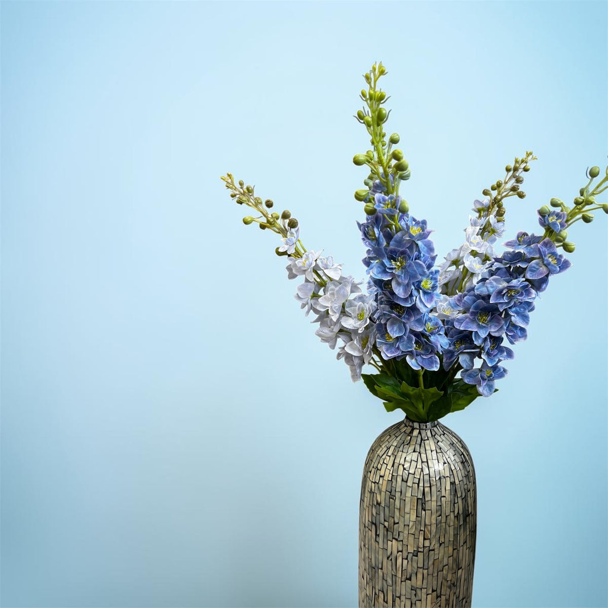 Azure Dream blue and white artificial bouquet with tall stems and layered greenery; vase shown for display only